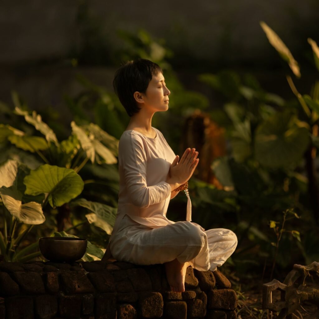 Serene scene of a woman meditating in a lush garden setting at daylight.