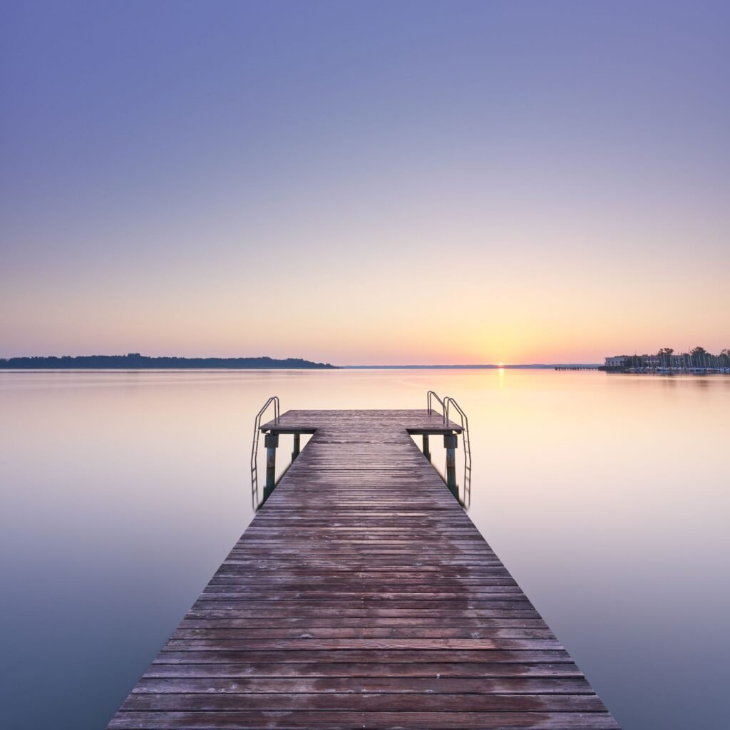 Serene sunset over Chiemsee with a wooden pier reflecting on still waters.